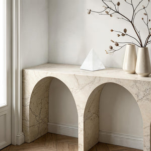 Symmetra statue on a marble console table with decorative vases