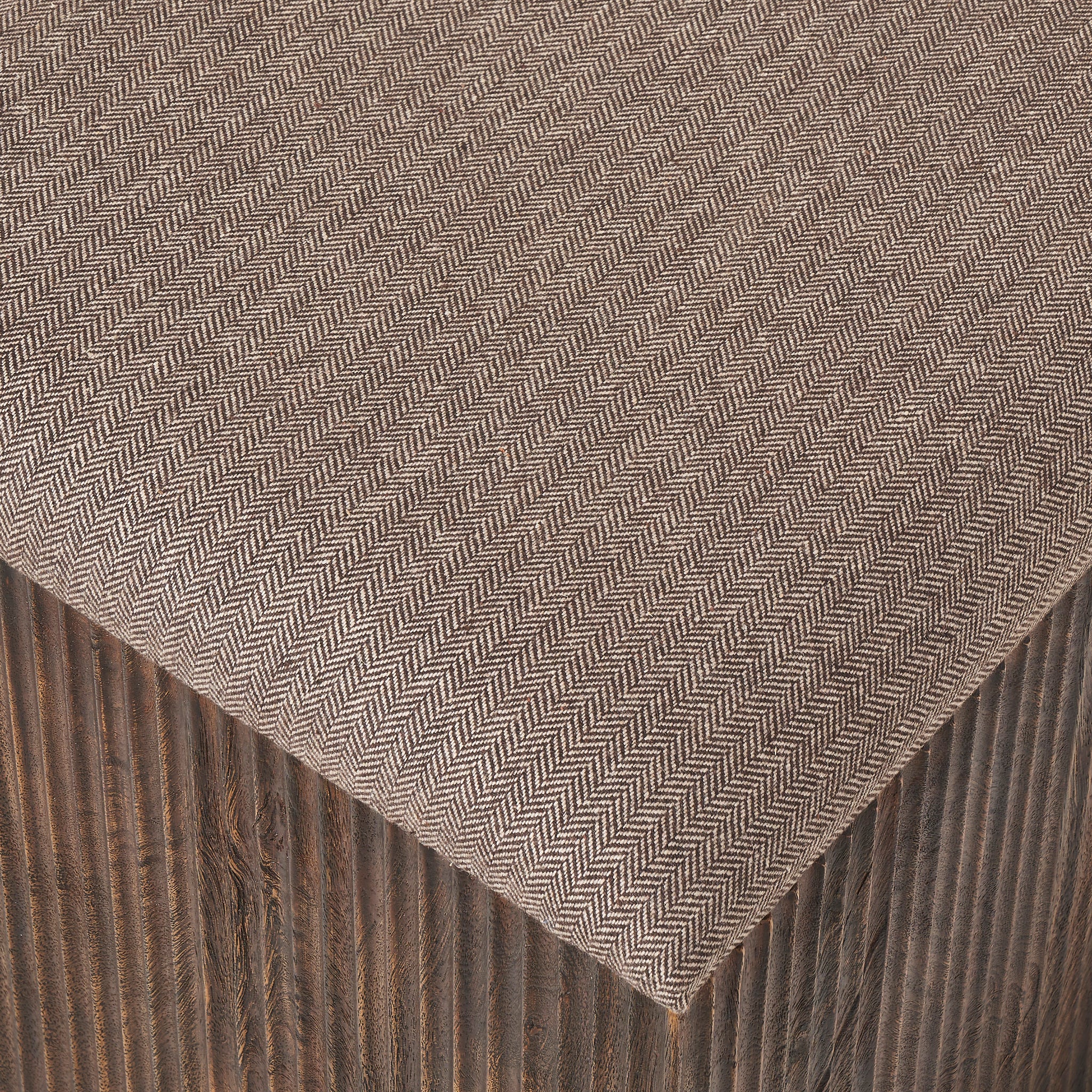 Close-up of Tristan stool's herringbone fabric top and dark wood base.