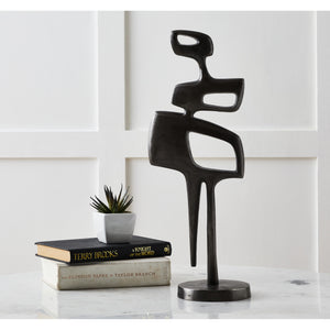 Pacino Indoor Aluminum Statue in Antique Nickel displayed on a table with books and a plant