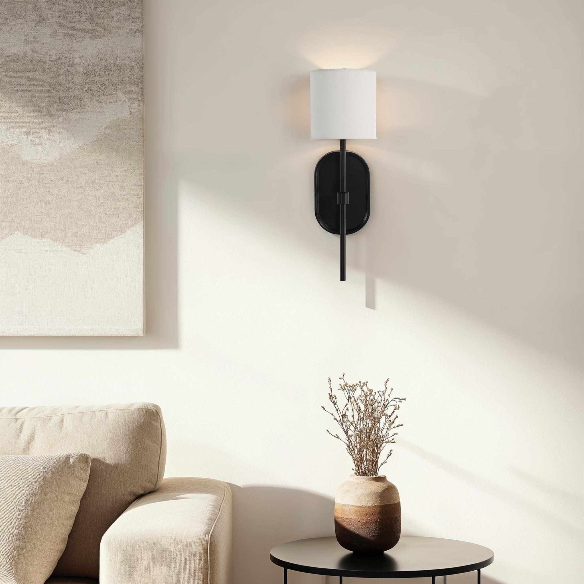 Fico Wall Sconce by Renwil installed in a living room, illuminating a beige wall.