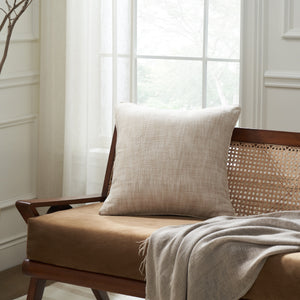 Amal indoor pillow placed on a wooden chair with a cozy throw blanket.