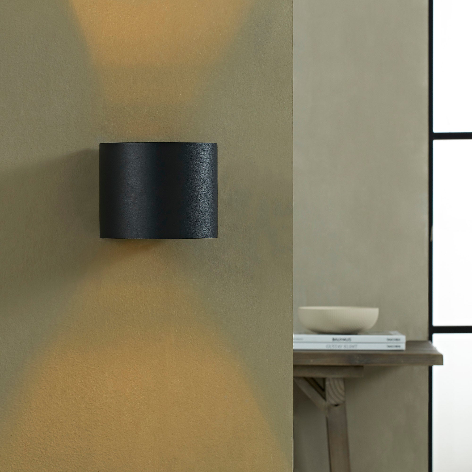 Lark Wall Sconce mounted on a wall, casting light with a gold interior.