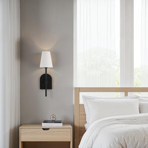 Mililani wall sconce installed beside a bed, illuminating a modern bedroom.