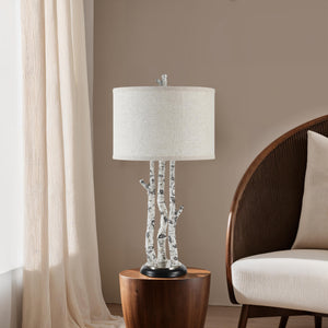 Naousa Table Lamp placed on a wooden side table next to a beige chair