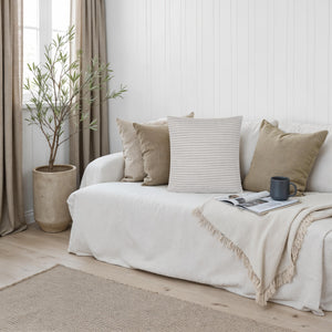 Lauren pillow among other pillows on a cozy couch with a plant