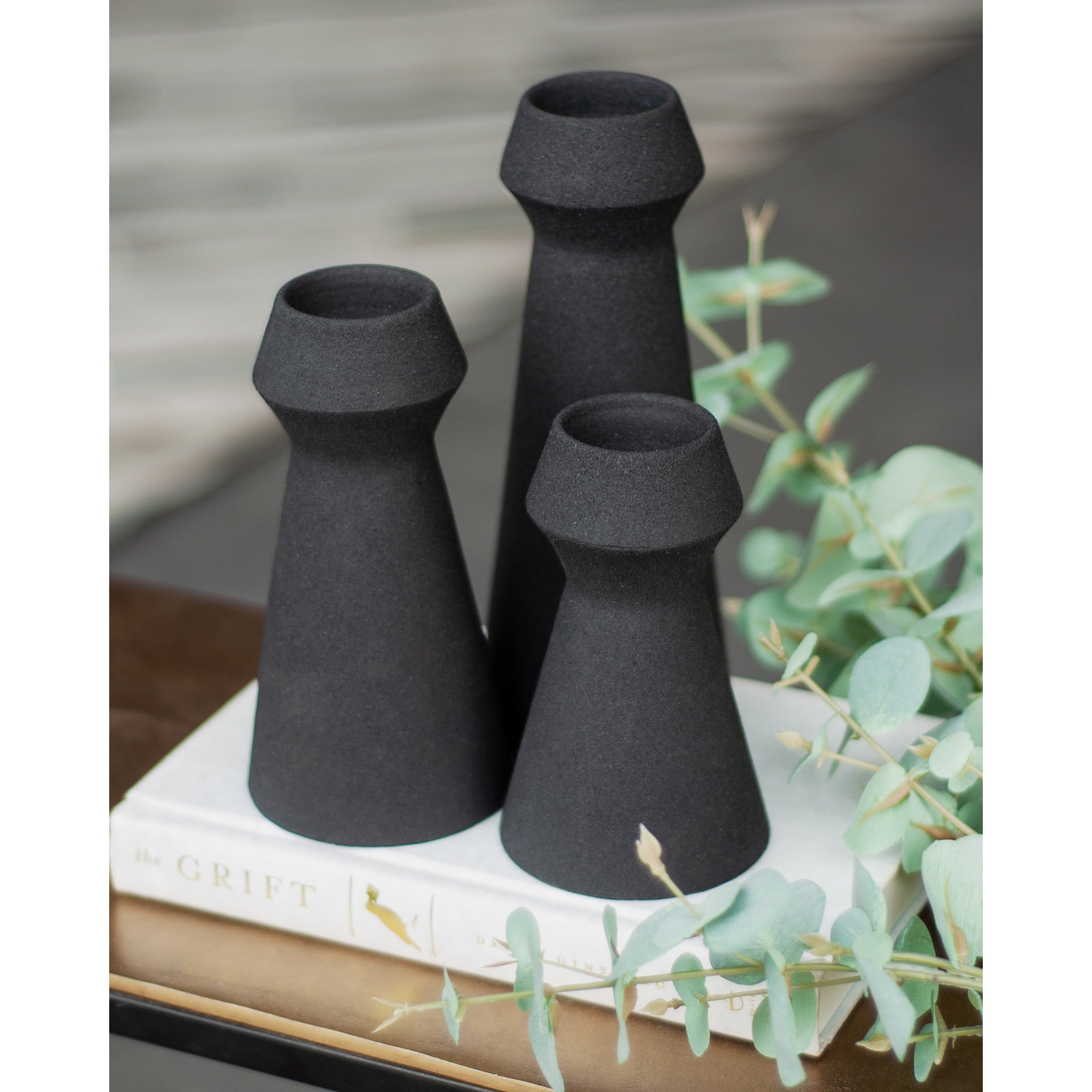 Granfeld Vase by Renwil in black, displayed with eucalyptus leaves on a coffee table.