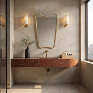 Echoa mirror with a wavy gold frame above a red marble sink in a modern bathroom setting.