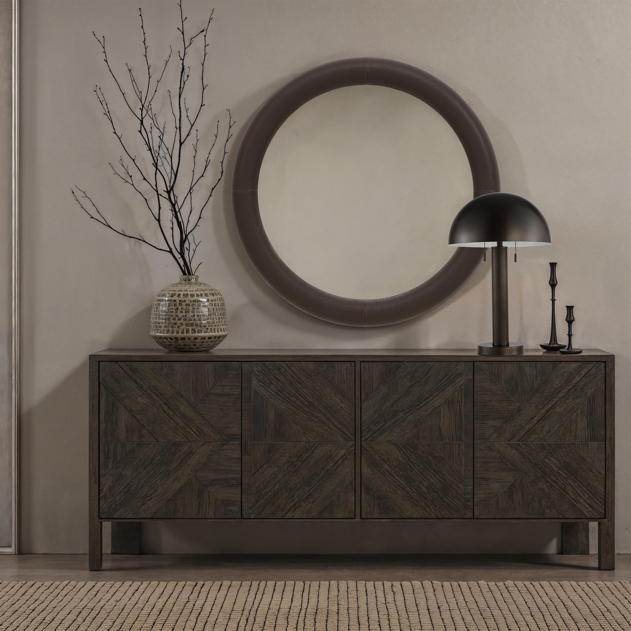Incanta floor lamp on a dark wooden sideboard with a round mirror and branches