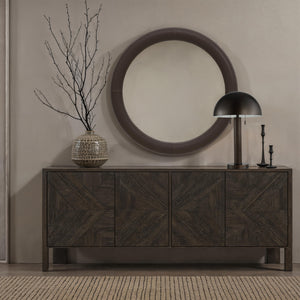 Incanta floor lamp on a dark wooden sideboard with a round mirror and branches