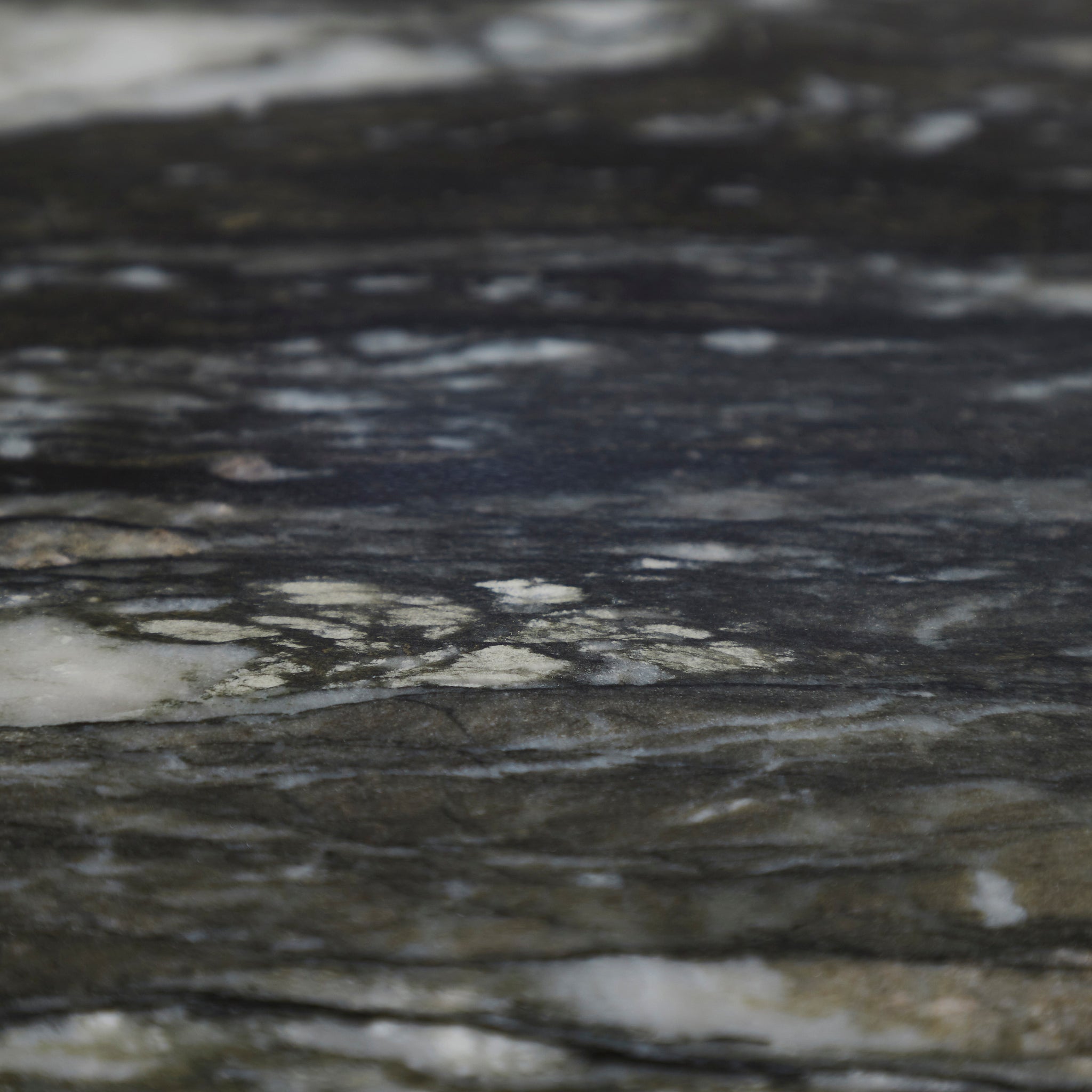 Close-up of a textured surface, resembling dark marble with white veining