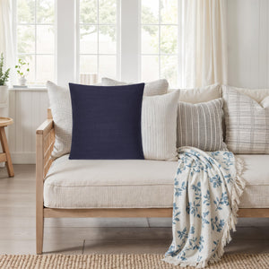 Forester decorative pillow on a light sofa surrounded by various textured cushions.
