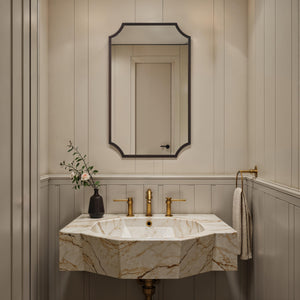Torre mirror by Renwil in a stylish bathroom setting above a marble sink with gold fixtures.