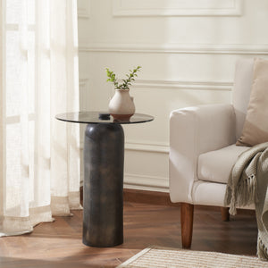 Arta accent table styled in a living room, showcasing a dark bronze base and a round black glass top with a plant.