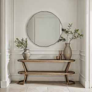 Cerro mirror by Renwil displayed above a wooden console table with vases and greenery.
