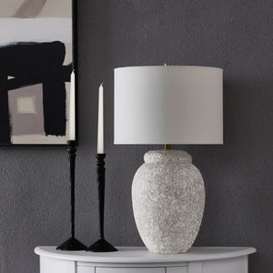 Wassily Table Lamp on a table with black candlesticks and abstract wall art in the background.