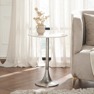 Eloa table beside a sofa, featuring a white marble top and a vase with dried flowers