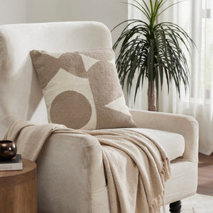 Ferla Indoor Pillow on a beige armchair with a plant and throw blanket