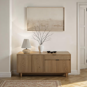 Noto Table Lamp on a wooden sideboard with a vase and decorative items.