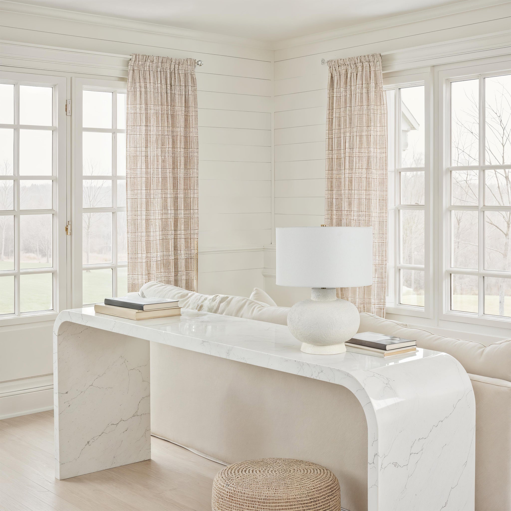 Mallow Table Lamp by Renwil placed on a marble console in a bright living room with large windows.