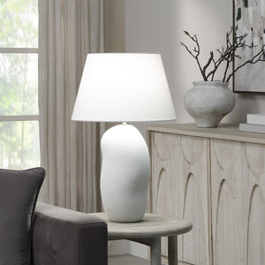 Katya Table Lamp on a side table in a living room setting with a neutral decor.