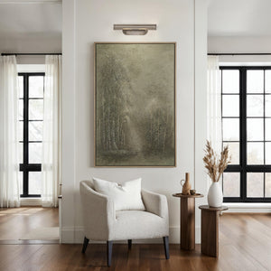 Rennes wall sconce illuminating a living space, mounted above a framed artwork.