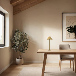 Ginevra table lamp in a modern workspace with a wooden desk and plant.