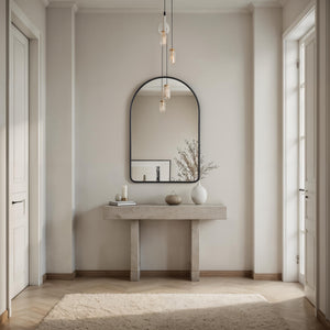 Cascais mirror with a black frame above a light stone console table in a modern entryway, featuring soft lighting and decorative vases.