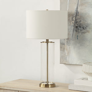Saco Table Lamp on a wooden table with a white shade and clear glass body
