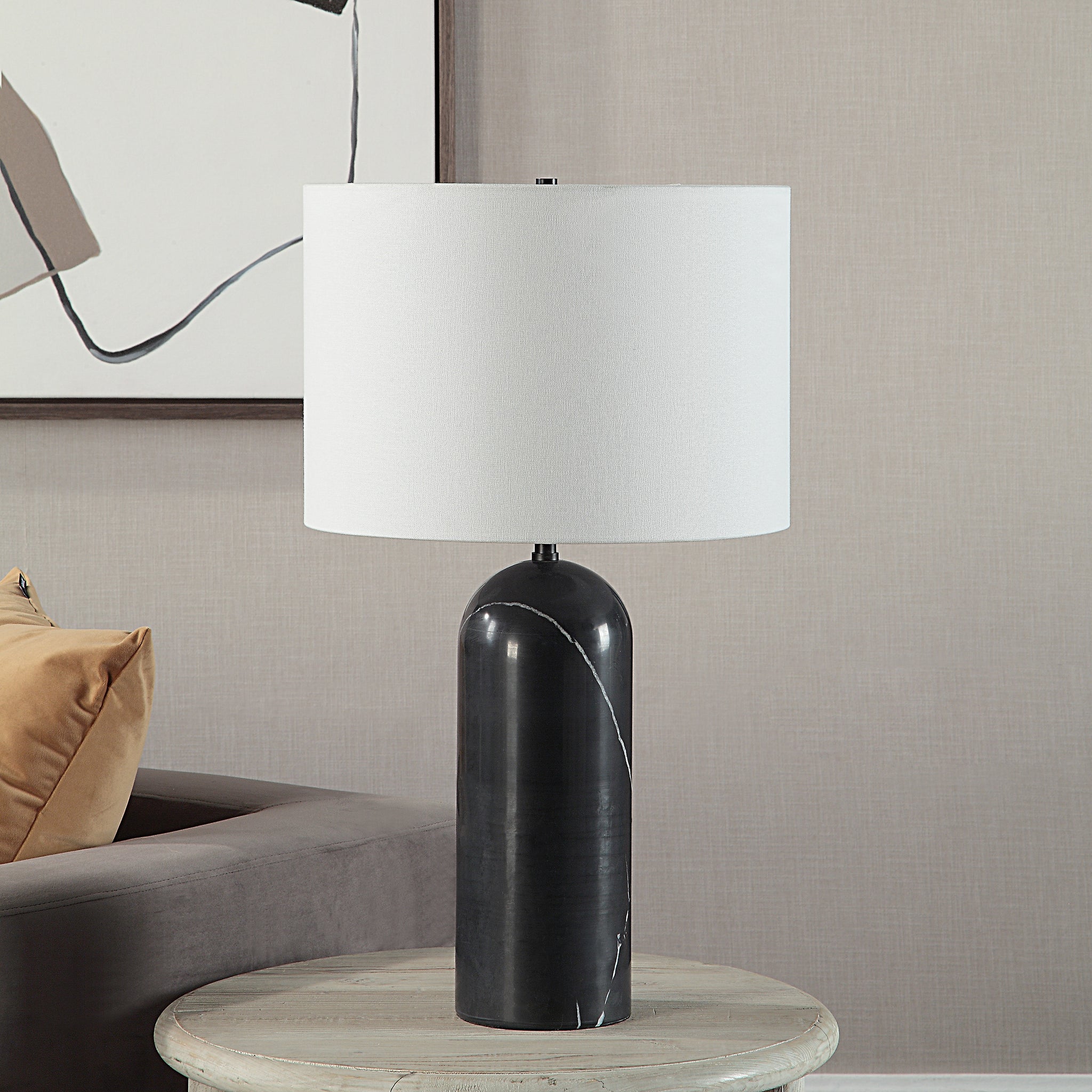 Tyne Table Lamp on a side table, showcasing black marble base and white shade in a living room setting.