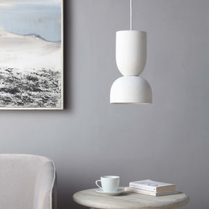 Kala Ceiling Fixture in a stylish setting, hanging above a table with a cup and books, against a gray wall.