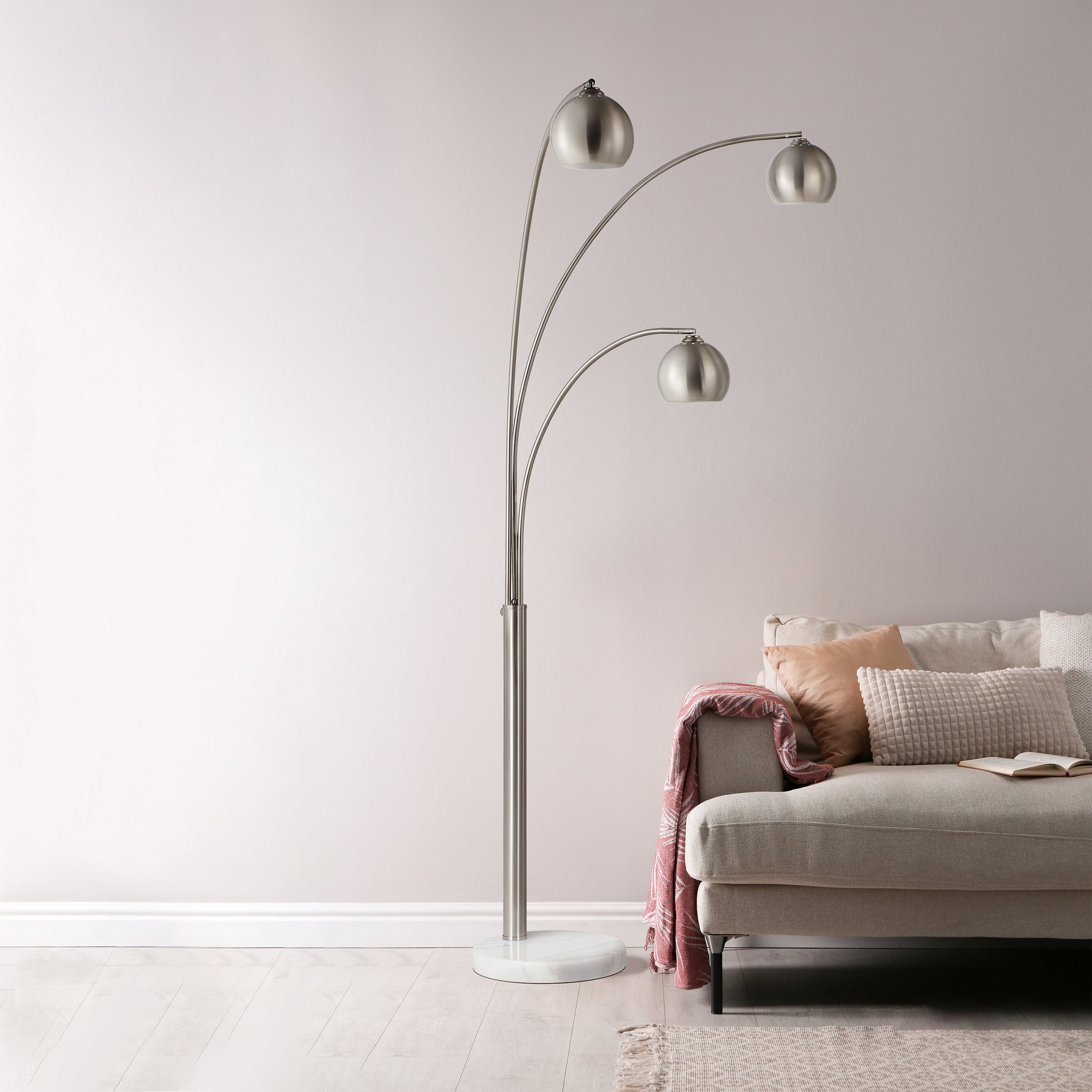 Aguillard floor lamp positioned next to a sofa, highlighting its three metallic shades and marble base.