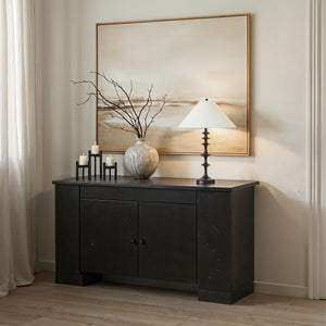 Petrus table lamp on a dark console table, paired with a vase and candles in a stylish interior setting.