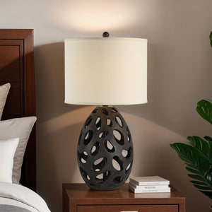 Loxley Table Lamp on a bedside table, featuring a black base and white shade in a cozy setting.