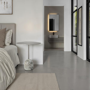 Aiden side table positioned next to a bed in a modern bedroom with a minimalist design.