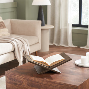 Ocra book holder displayed on a wooden table with an open book, set in a cozy living room.