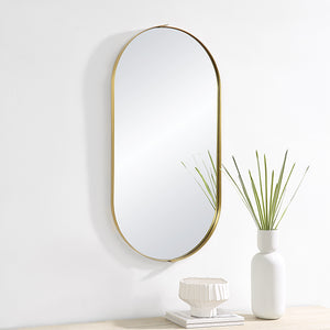 Aleah Wall Mirror mounted on a wall beside a white vase and decorative items.