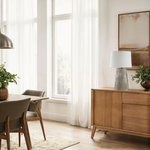 Calma Table Lamp placed on a wooden sideboard in a bright room
