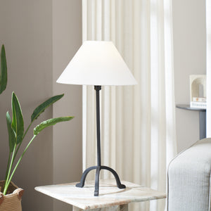 Kitts table lamp on a marble side table, with a white shade and black base, surrounded by greenery.