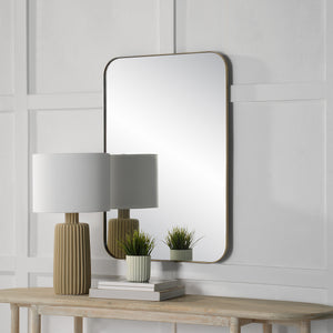 Vesey Wall Mirror displayed above a wooden table with a lamp and potted plants.