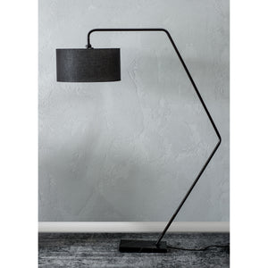 Penelin Floor Lamp positioned against a textured wall, highlighting its black shade and modern design.