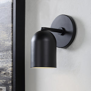 Valonia Wall Sconce in black mounted on a wall beside artwork