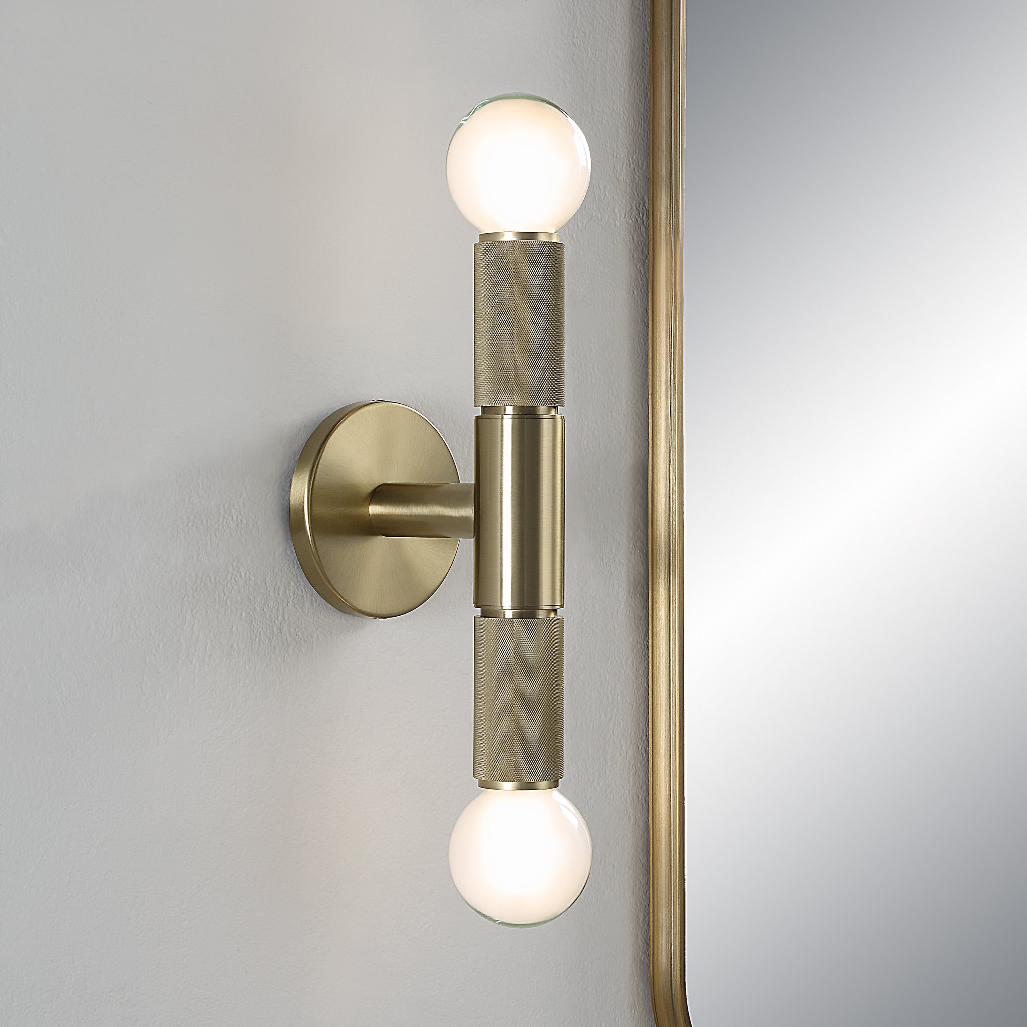 Tovi Wall Sconce mounted on wall with two illuminated globes and mirror reflection