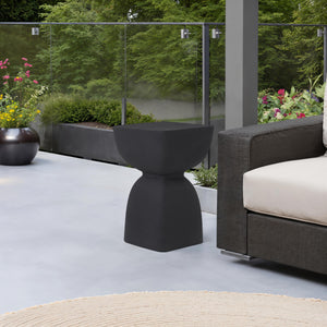Frans Outdoor Side Table in black on a patio, next to a sofa and plants.