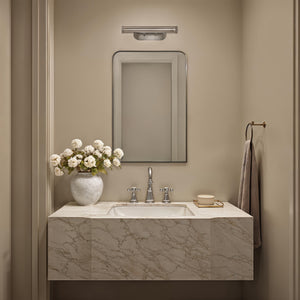 Jackline mirror above a marble sink in a bathroom, complemented by a vase of white flowers.
