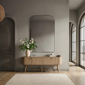Opalina mirror displayed in a modern interior, above a wooden console with flowers.