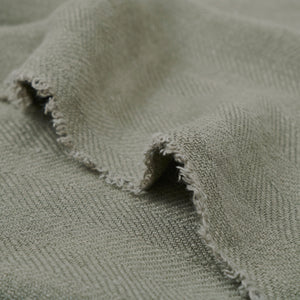 Vernier Throw in light green, draped to show frayed edges and herringbone pattern.