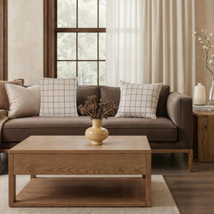 Thornhill pillows on a brown sofa with a wooden coffee table and decorative vase.