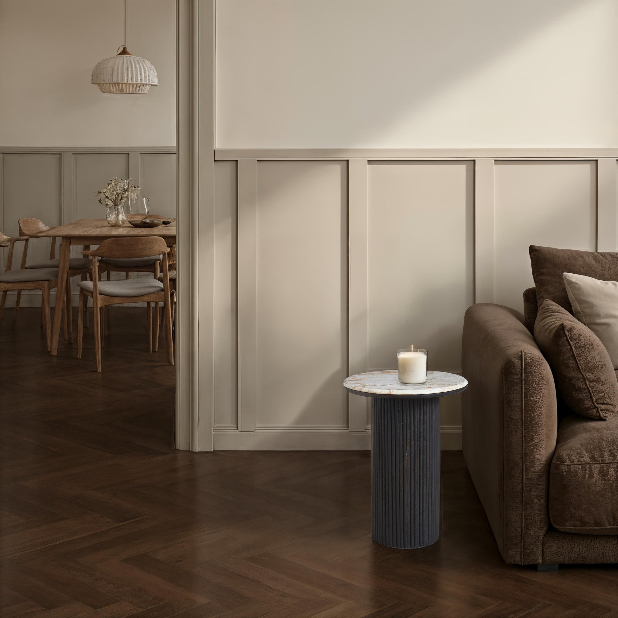 Alessio accent table with a candle next to a brown sofa in a cozy living space.