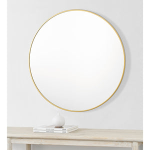 Alegre Wall Mirror mounted on a wall above a table with decor.