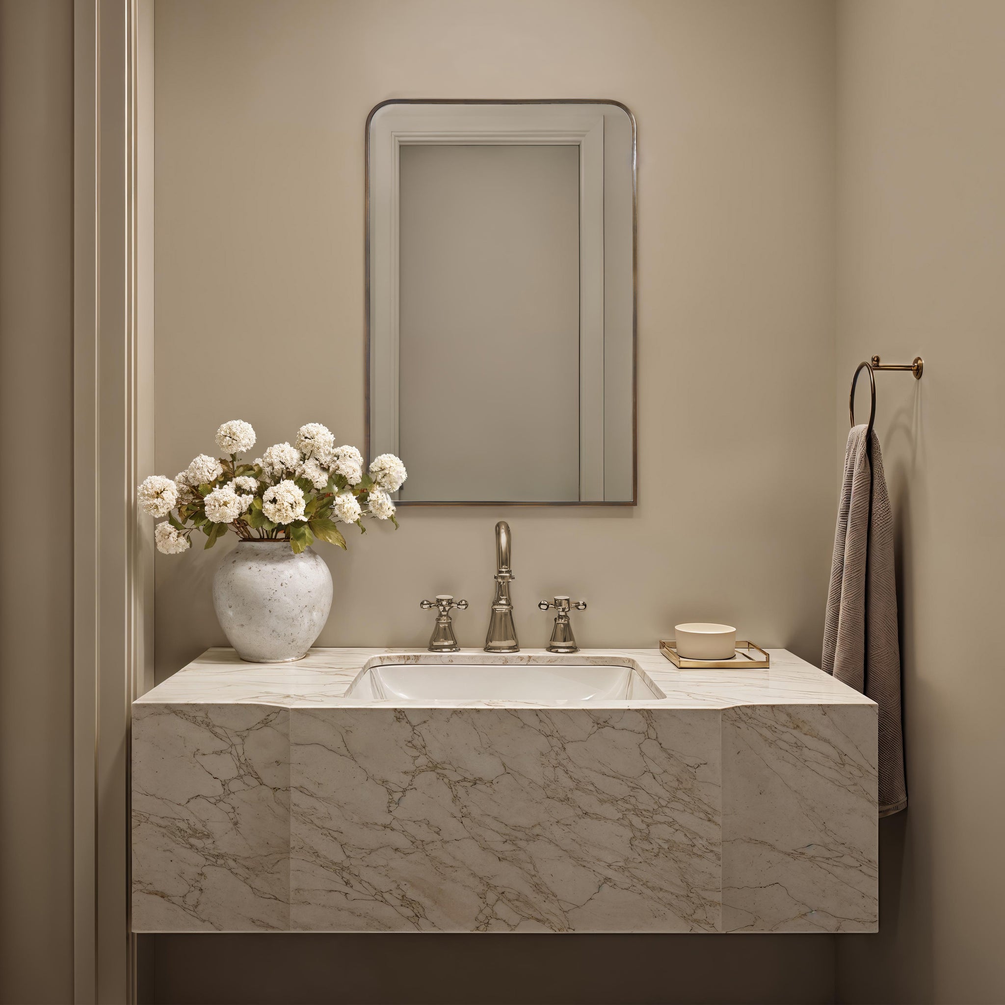 Jackline mirror by Renwil above a marble sink with a vase of white flowers.